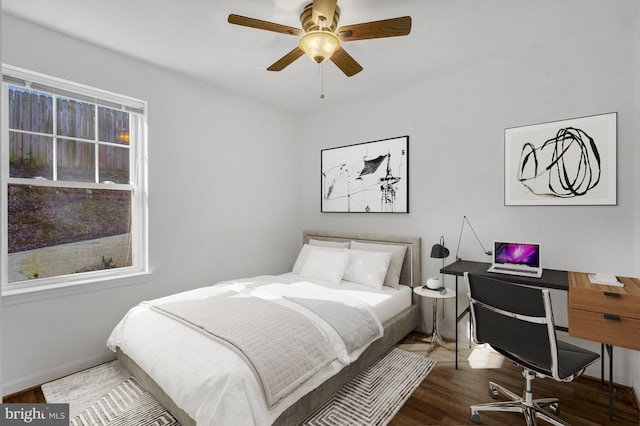 bedroom with a ceiling fan, wood finished floors, and baseboards