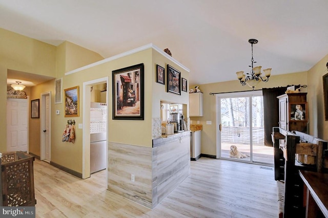 foyer featuring an inviting chandelier, lofted ceiling, and light wood finished floors