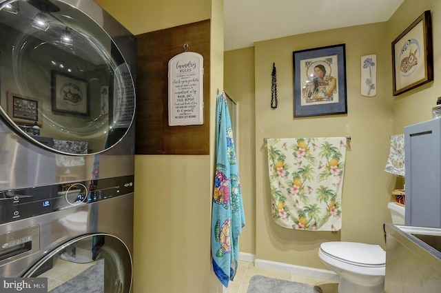 bathroom with stacked washer and dryer, toilet, and tile patterned flooring