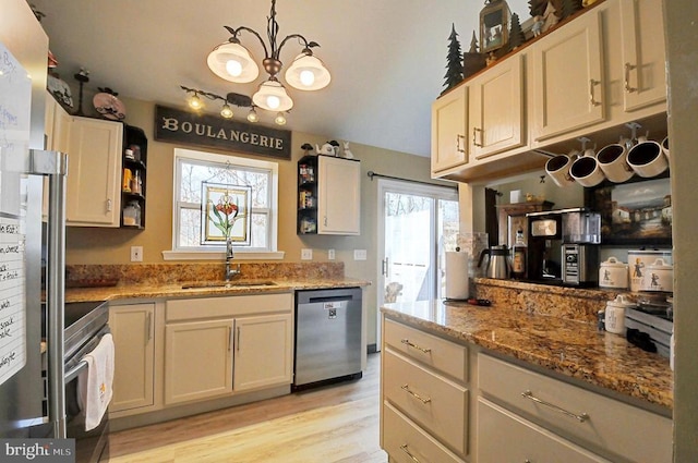 kitchen featuring light stone counters, light wood-style flooring, stainless steel appliances, and a sink