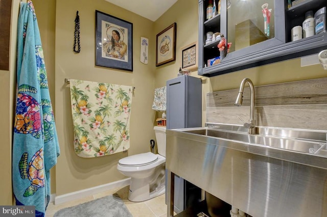 bathroom with tile patterned flooring, toilet, baseboards, and a sink