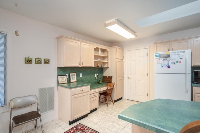 kitchen featuring white fridge, built in desk, backsplash, and light tile patterned floors