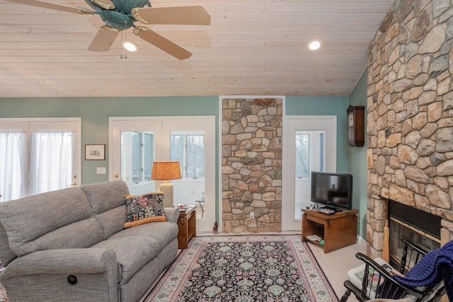 tiled living room featuring vaulted ceiling, a stone fireplace, plenty of natural light, and wooden ceiling