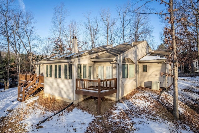 snow covered back of property with a wooden deck