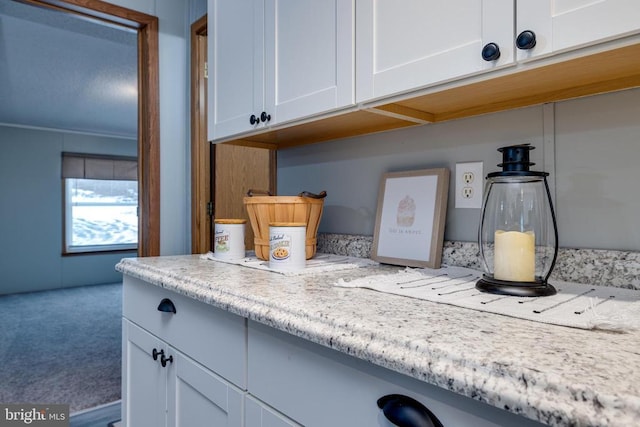 kitchen with carpet, white cabinets, and light stone counters