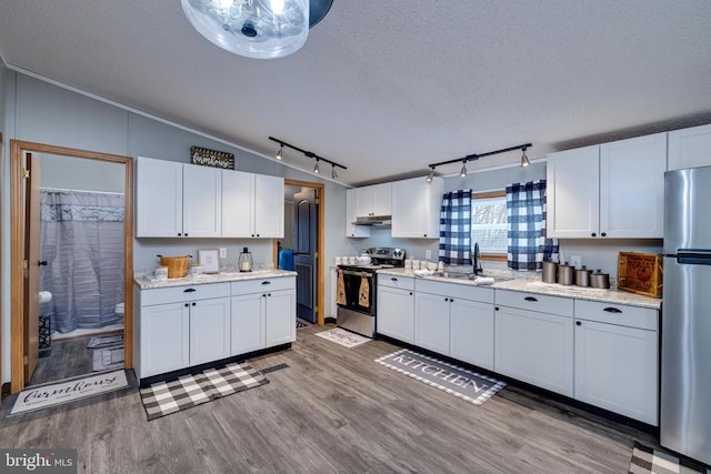 kitchen featuring sink, white cabinetry, vaulted ceiling, appliances with stainless steel finishes, and hardwood / wood-style flooring