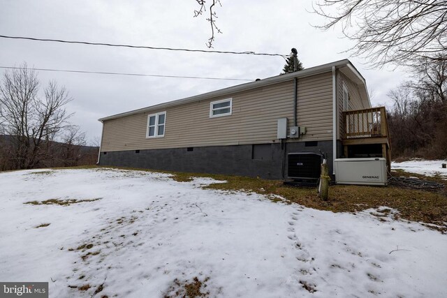 snow covered rear of property featuring central AC