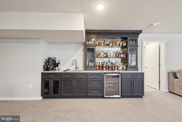 bar with beverage cooler, baseboards, a sink, wet bar, and light carpet