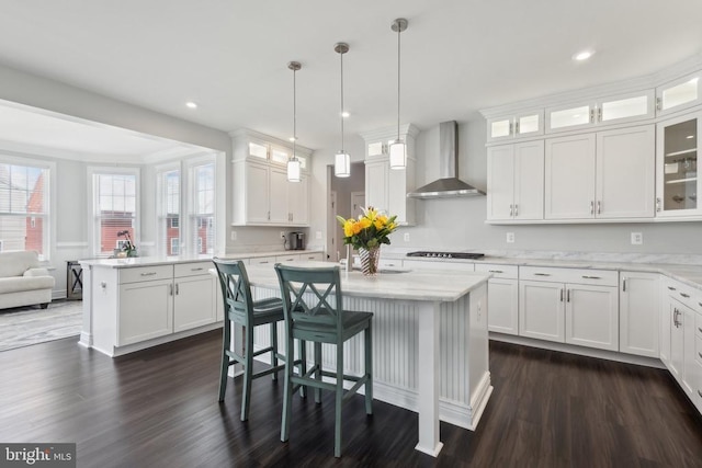 kitchen featuring wall chimney exhaust hood, dark wood-style flooring, a center island, white cabinets, and gas stovetop