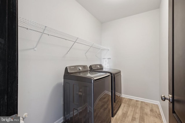 laundry area featuring laundry area, washer and clothes dryer, baseboards, and light wood-style floors