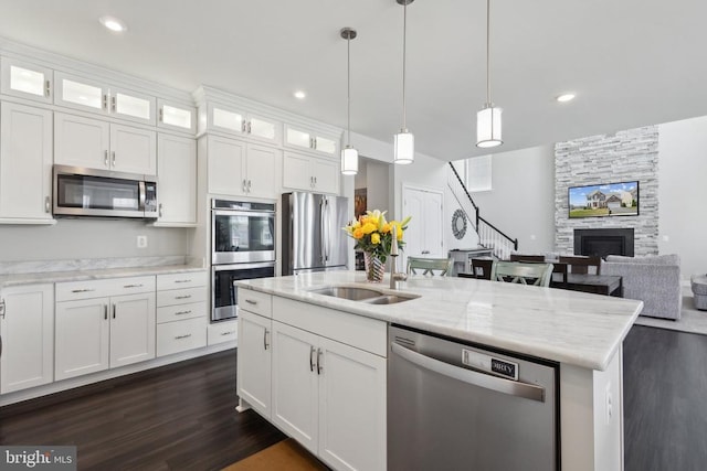 kitchen featuring a stone fireplace, a sink, appliances with stainless steel finishes, and dark wood-style floors
