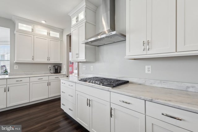 kitchen with glass insert cabinets, wall chimney exhaust hood, white cabinetry, dark wood-type flooring, and stainless steel gas stovetop