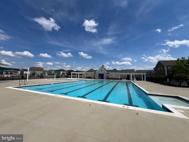 community pool featuring a patio, fence, and a residential view