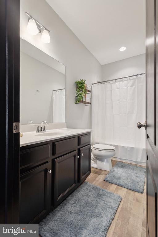 bathroom featuring vanity, toilet, shower / bath combo with shower curtain, and wood finished floors