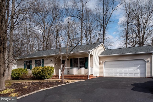 ranch-style house featuring a garage, covered porch, and driveway