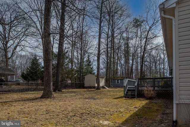 view of yard with a deck, an outbuilding, and fence