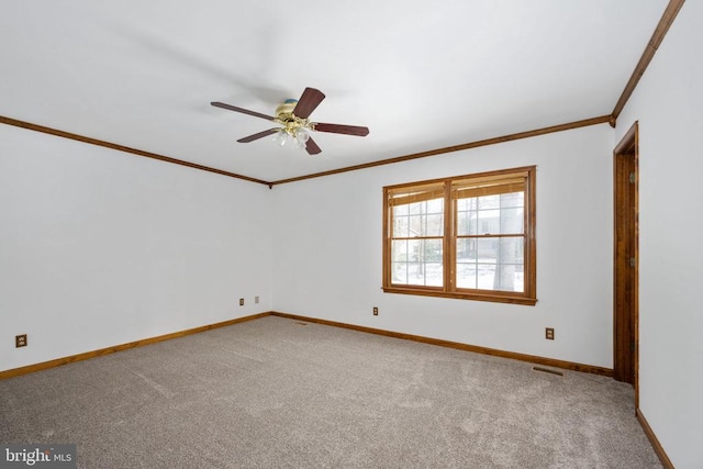 spare room with visible vents, ornamental molding, carpet floors, baseboards, and ceiling fan