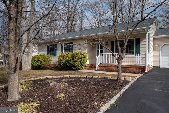 ranch-style house with a porch, driveway, and roof with shingles