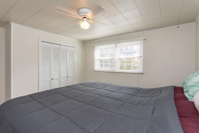 bedroom featuring ceiling fan, ornamental molding, and a closet