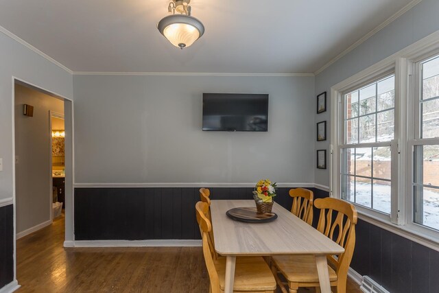 dining area featuring dark hardwood / wood-style flooring, crown molding, a wealth of natural light, and a baseboard radiator