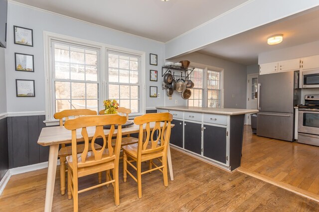 dining space featuring ornamental molding and light hardwood / wood-style floors