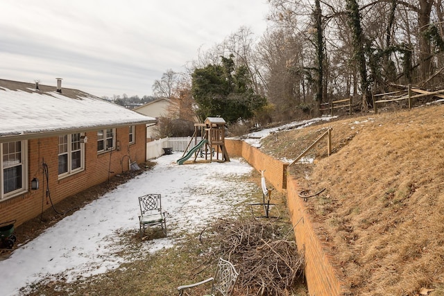 snowy yard featuring a playground