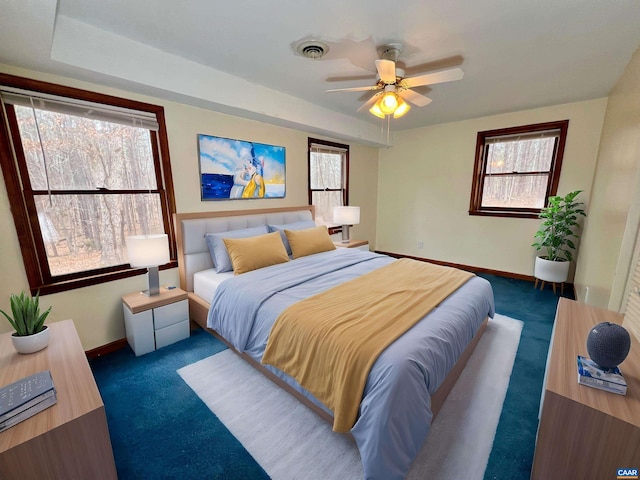 bedroom with visible vents, multiple windows, and dark carpet