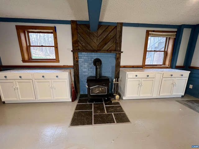 interior space with a wood stove, a wainscoted wall, and a textured ceiling