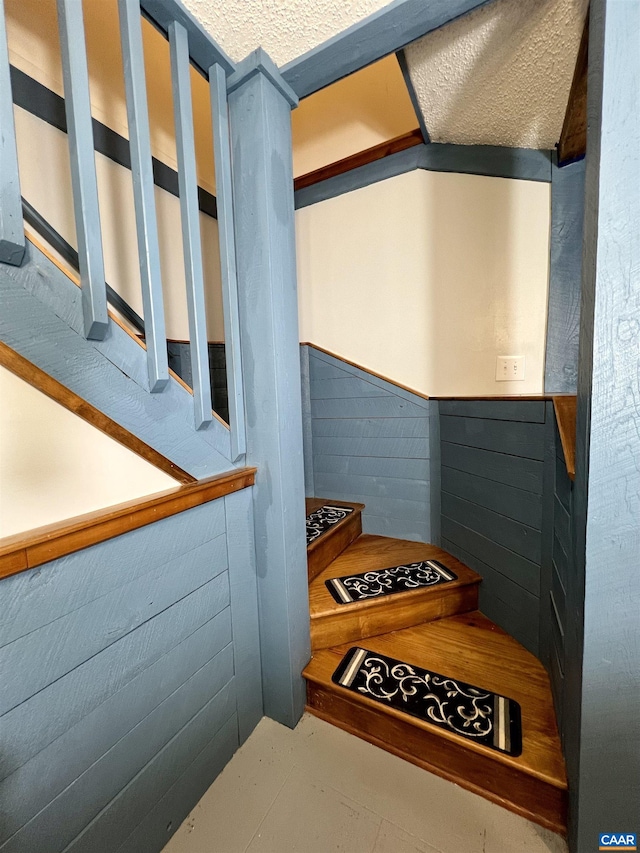 stairs featuring wooden walls and wainscoting