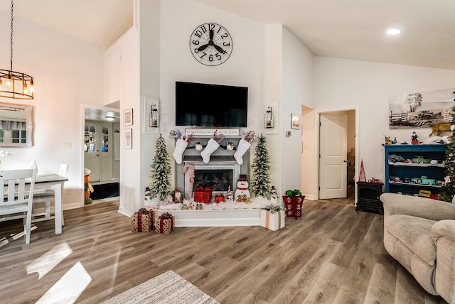 living room featuring hardwood / wood-style floors, a notable chandelier, and high vaulted ceiling