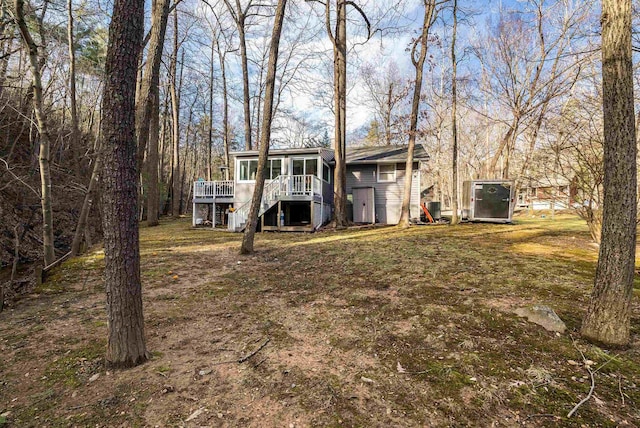 rear view of property with a yard, a sunroom, and a deck