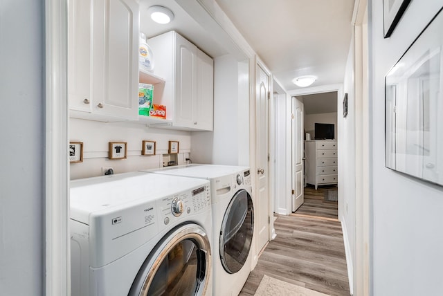 laundry room featuring cabinets, washing machine and dryer, and light hardwood / wood-style flooring