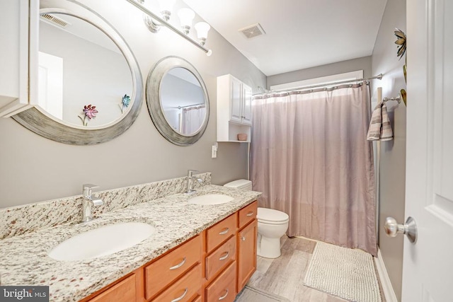 bathroom with toilet, visible vents, a sink, and wood finished floors