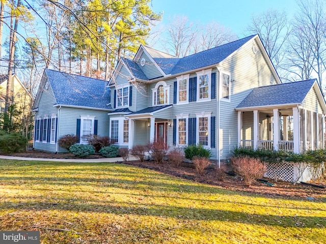 view of front facade with roof with shingles and a front yard