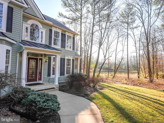 property entrance with metal roof, a standing seam roof, and a lawn