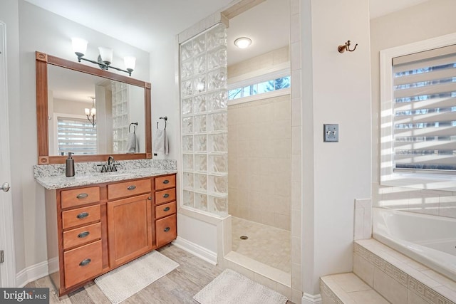 bathroom with a garden tub, wood finished floors, vanity, baseboards, and walk in shower