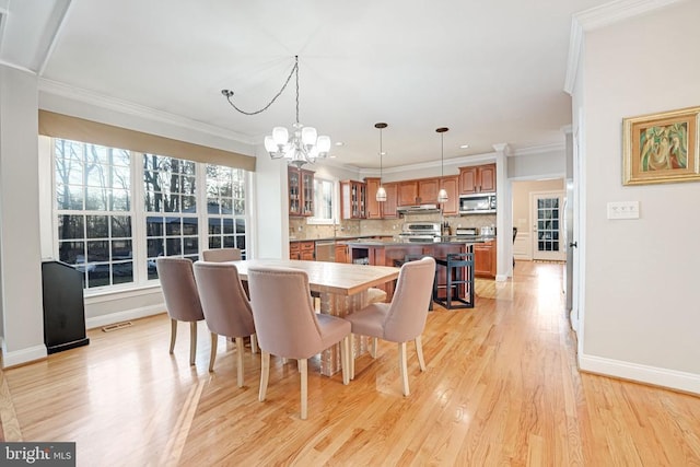 dining area with crown molding, light wood finished floors, visible vents, an inviting chandelier, and baseboards