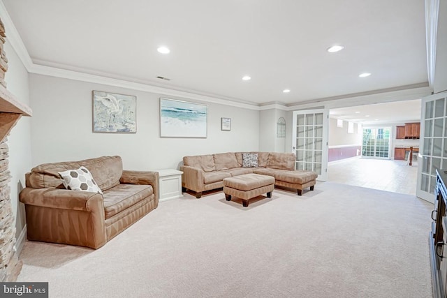 carpeted living area with a stone fireplace, recessed lighting, visible vents, french doors, and ornamental molding