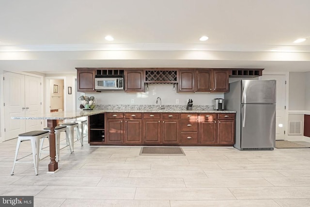 kitchen with visible vents, light stone counters, stainless steel appliances, a sink, and recessed lighting