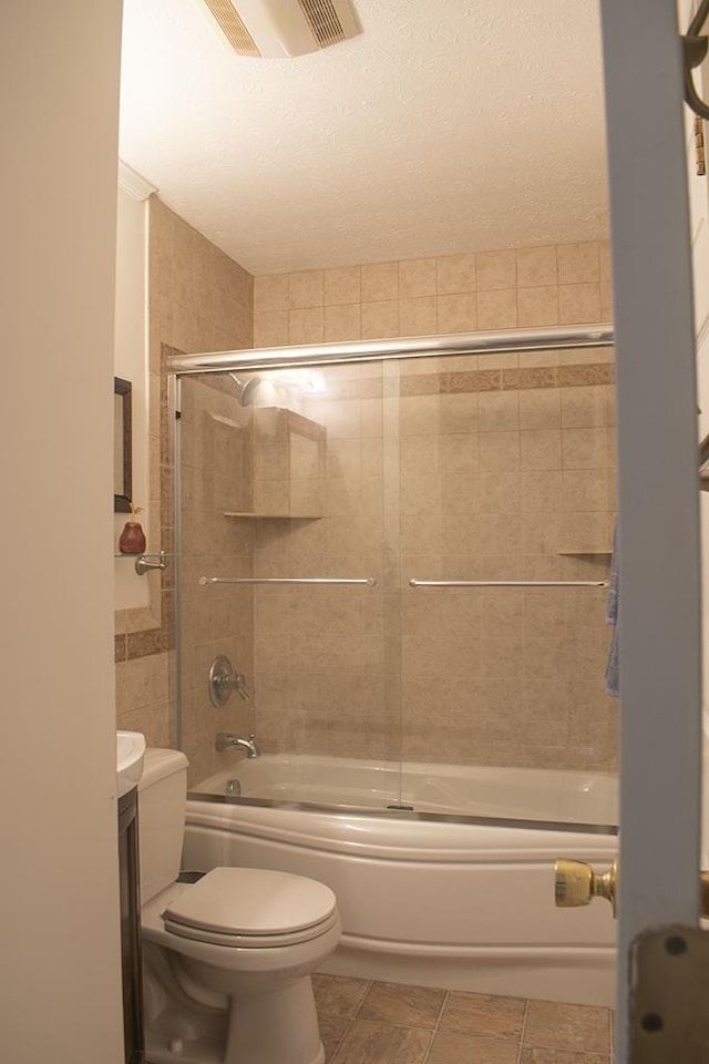 full bathroom featuring shower / bath combination with glass door, tile walls, vanity, tile patterned floors, and toilet