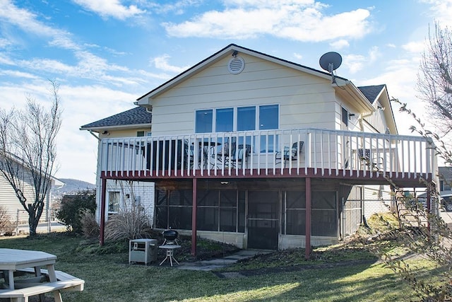 rear view of house featuring a yard, a sunroom, and a deck