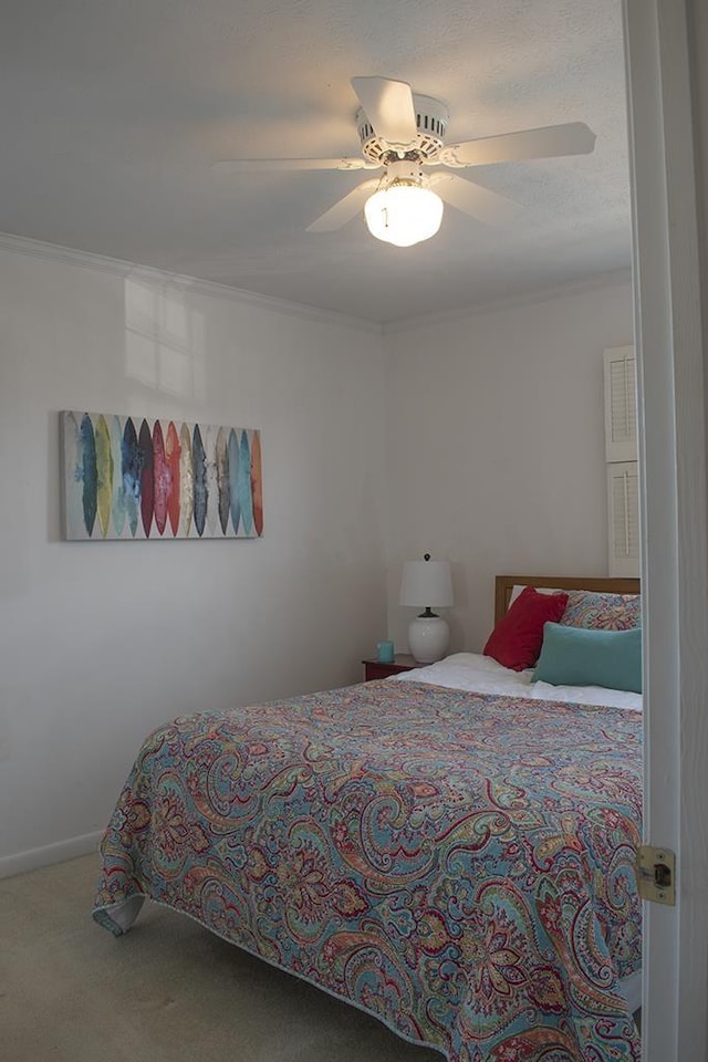 carpeted bedroom featuring crown molding and ceiling fan