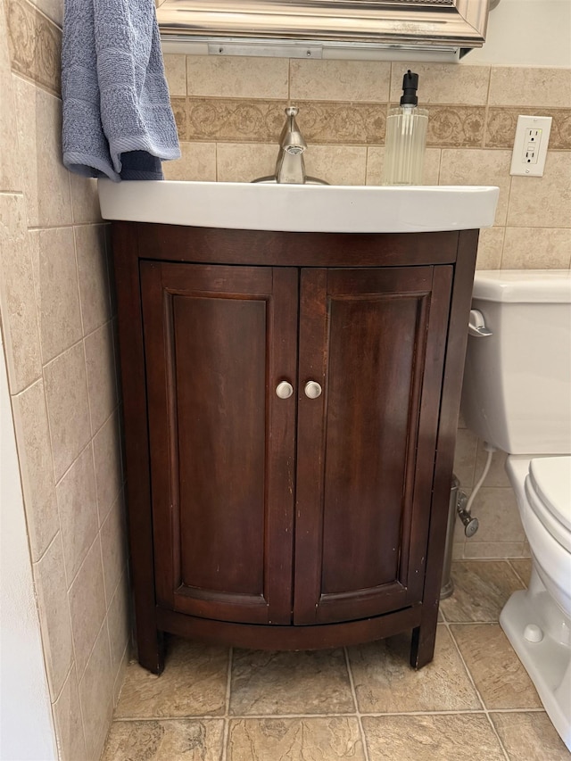 bathroom featuring vanity, tile walls, and toilet