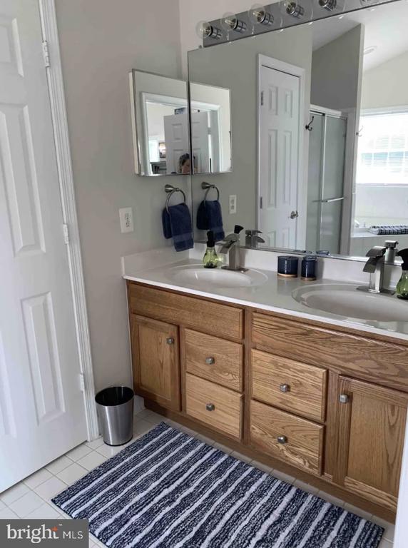 bathroom featuring tile patterned flooring, vanity, and an enclosed shower