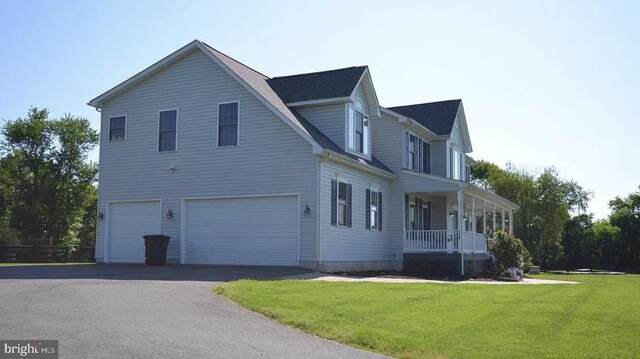 view of property exterior with a porch, a garage, and a lawn