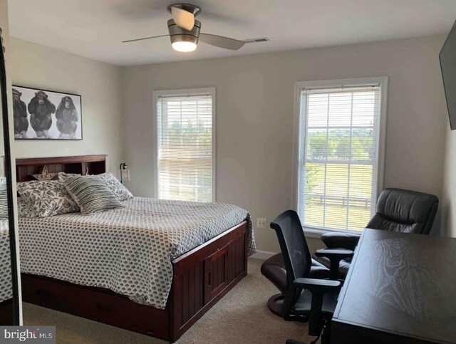 bedroom with ceiling fan, light colored carpet, and multiple windows