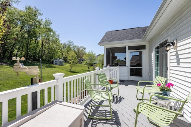 wooden deck with a lawn, an outbuilding, a sunroom, and a shed