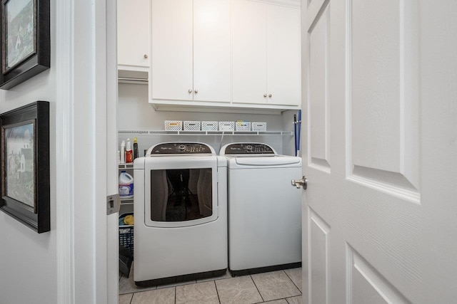 washroom featuring independent washer and dryer, light tile patterned flooring, and cabinet space