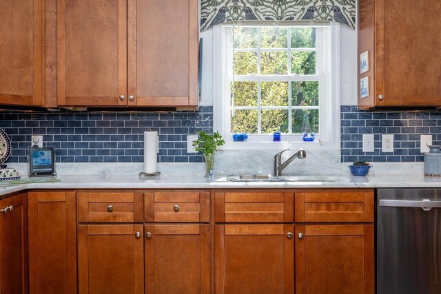 kitchen with decorative backsplash, brown cabinetry, stainless steel dishwasher, light countertops, and a sink