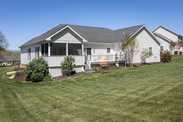 rear view of property with a lawn, a sunroom, and a deck
